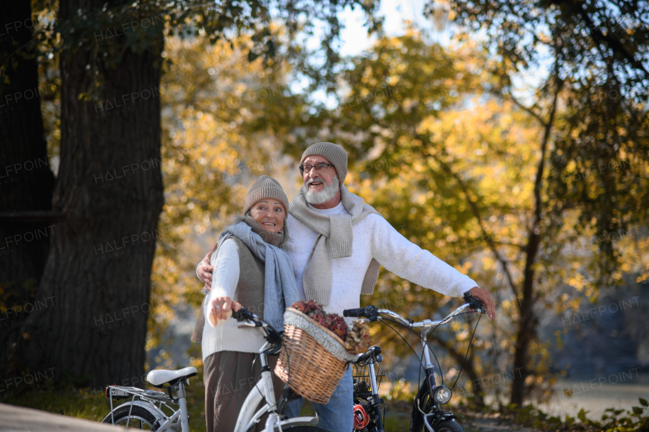 Elderly couple on walk in park, pushing their bikes side by side. Seniors in love on stroll through autumn city, enjoying a peaceful moment.