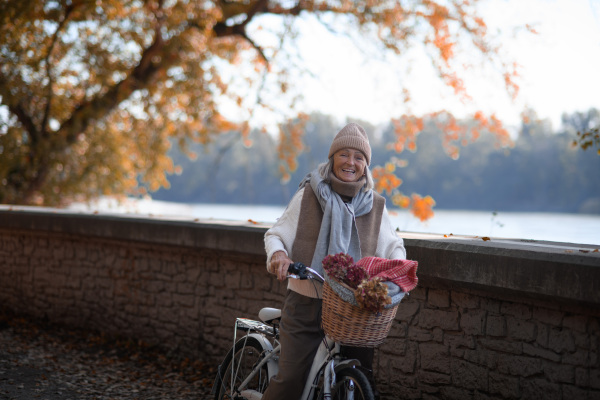 Seniow woman riding bicycle in autumn park, enjoying a peaceful moment outdoor alone