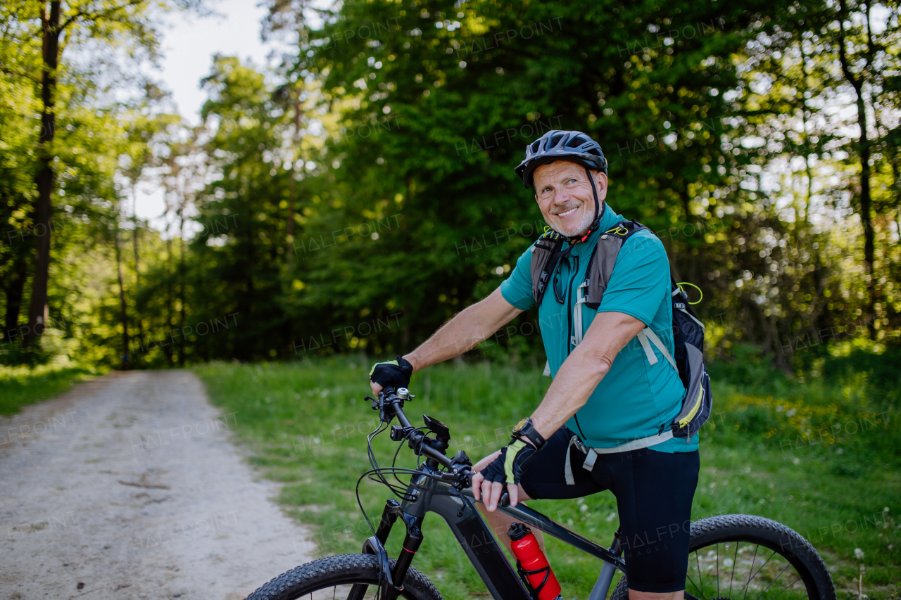 An active senior man riding bicycle at summer park, healthy lifestyle concept.