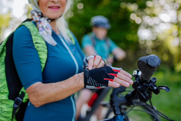 Close-up of a senior woman biker putting on bicycle gloves.