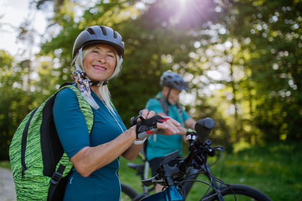 A happy senior woman biker putting on bicycle gloves.