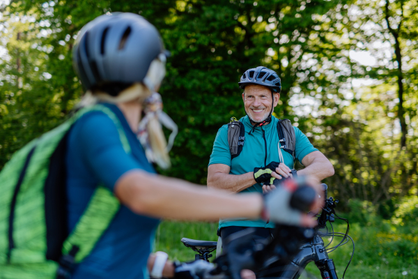 A portrait of active senior couple riding bicycles at summer park, healthy lifestyle concept.