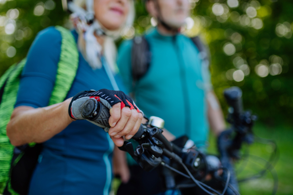 A close-up of senior couple riding bicycles, woman biker holding to handlebars.