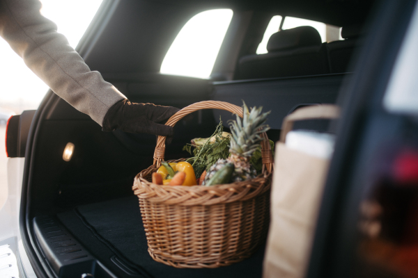 Close-up of somebody giving his purchase in the electric car trunk.