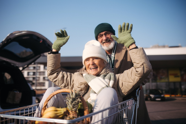 Senior couple going home from a grocery store, having fun.