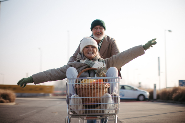 Senior couple going home from a grocery store, having fun.