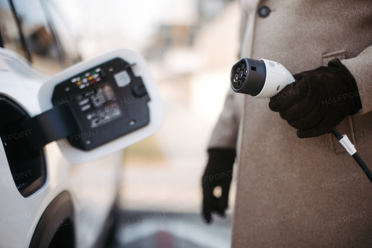 Close up of a unrecognizable man charging electric car.