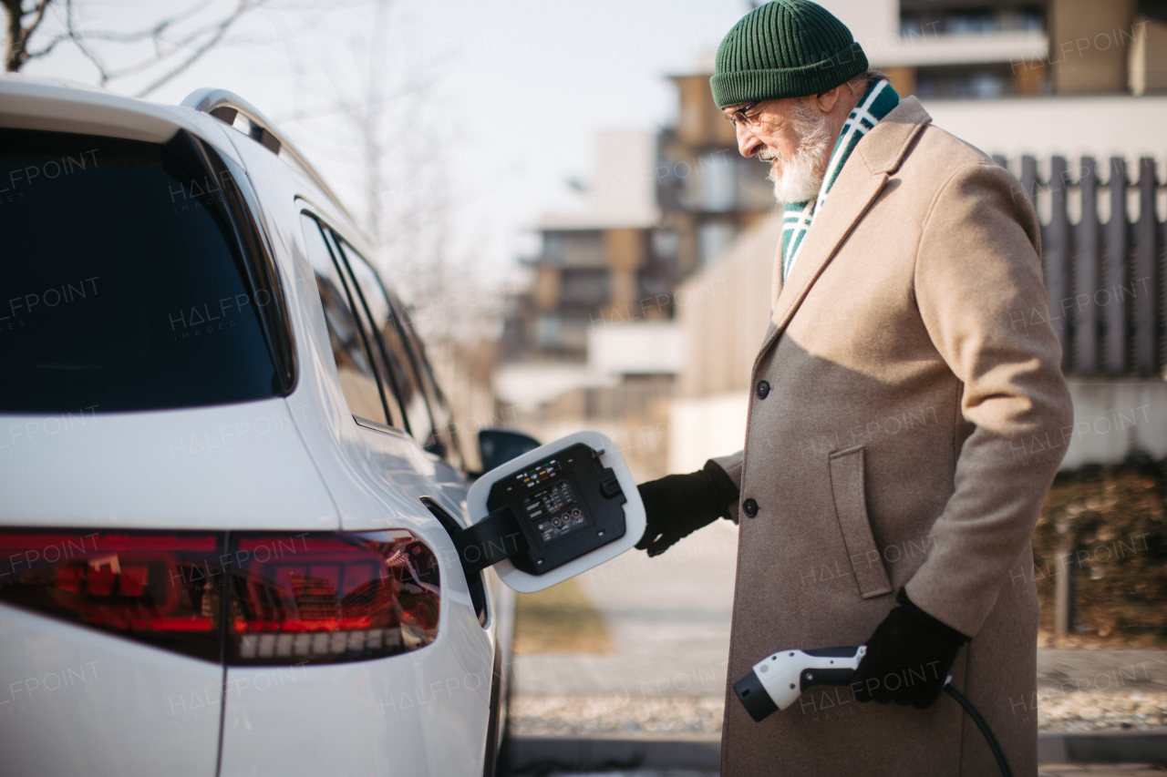 Close up of a senior man charging electric car.