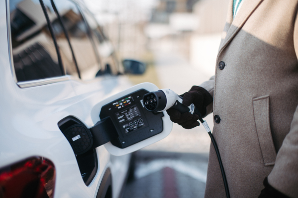 Close up of a senior man charging electric car.