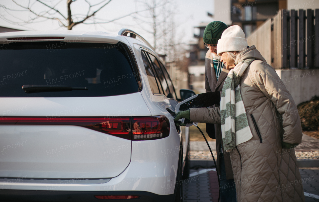 Close up of a senior woman charging electric car.