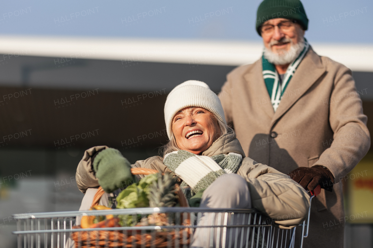 Senior couple going home from a grocery store, having fun.