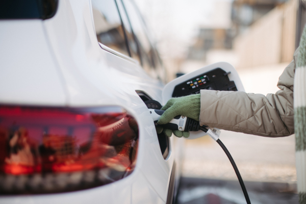 Close up of a unrecognizable woman charging electric car.