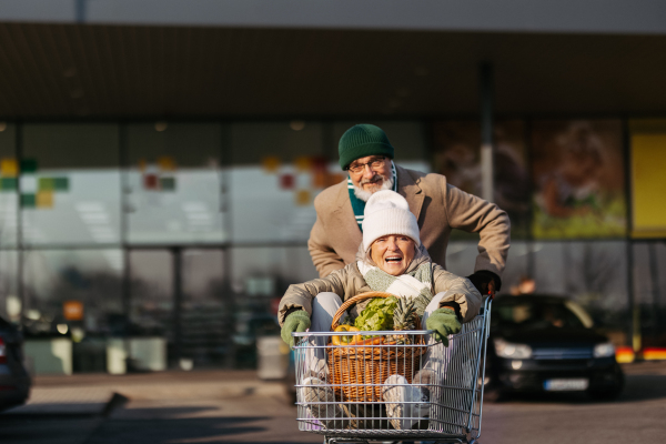 Senior couple going home from a grocery store, having fun.