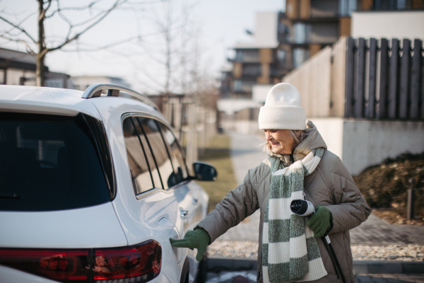 Close up of a senior woman charging electric car.