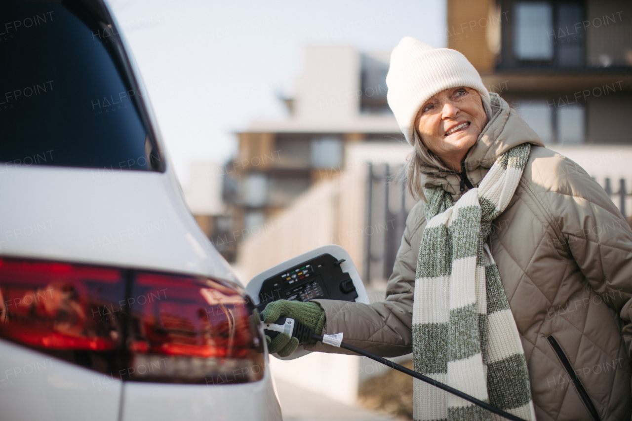 Close up of a senior woman charging electric car.