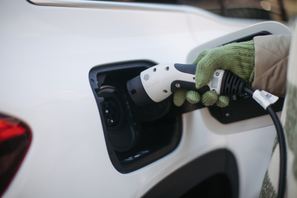 Close up of a unrecognizable woman charging electric car.