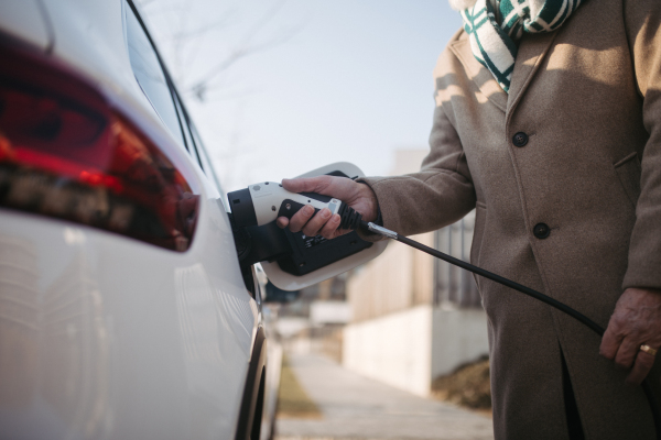 Close up of a senior man charging electric car.