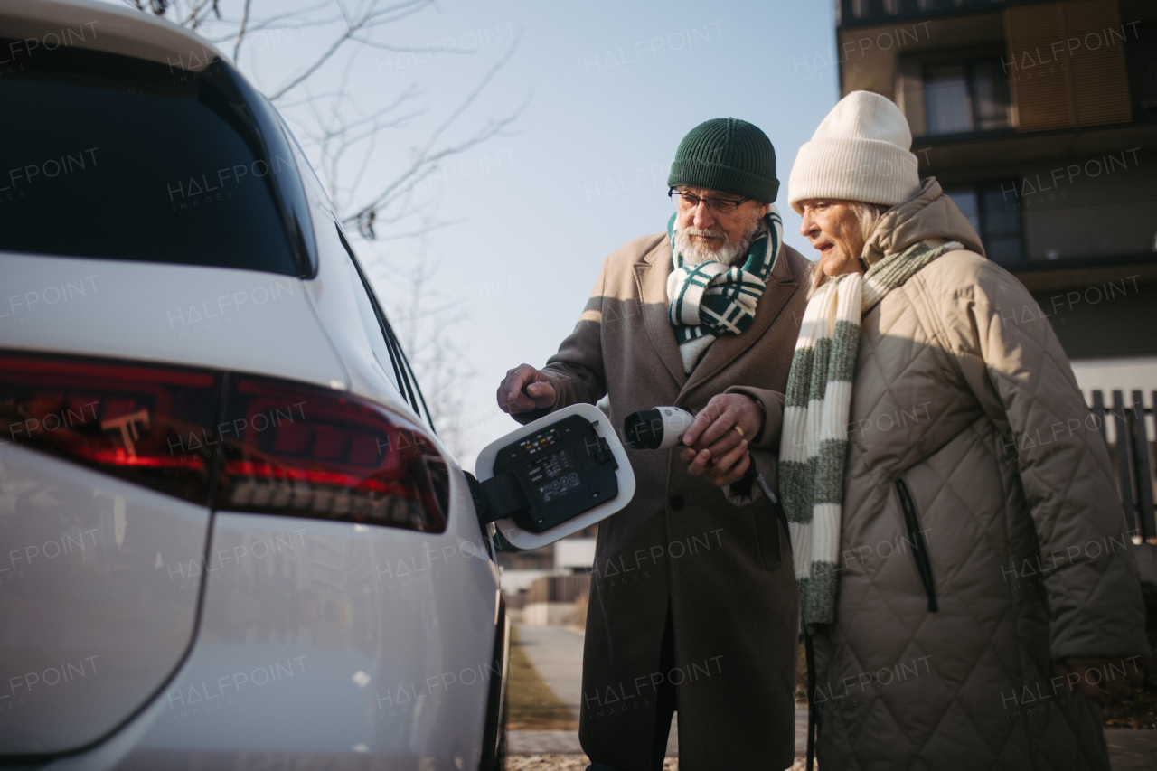 Close up of a senior couple charging electric car.