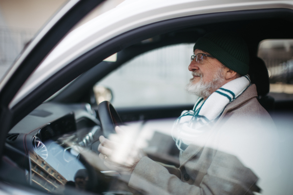 A senior man driving a car, close-up.