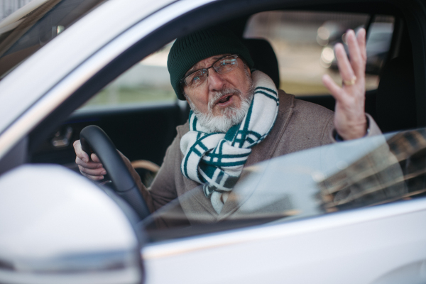 Angry senior man driving a car, close-up.