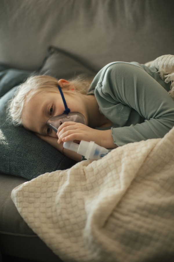 LIttle sick girl using an inhaler during flu.