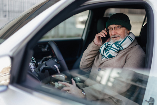 Senior mansitting in the car and calling.