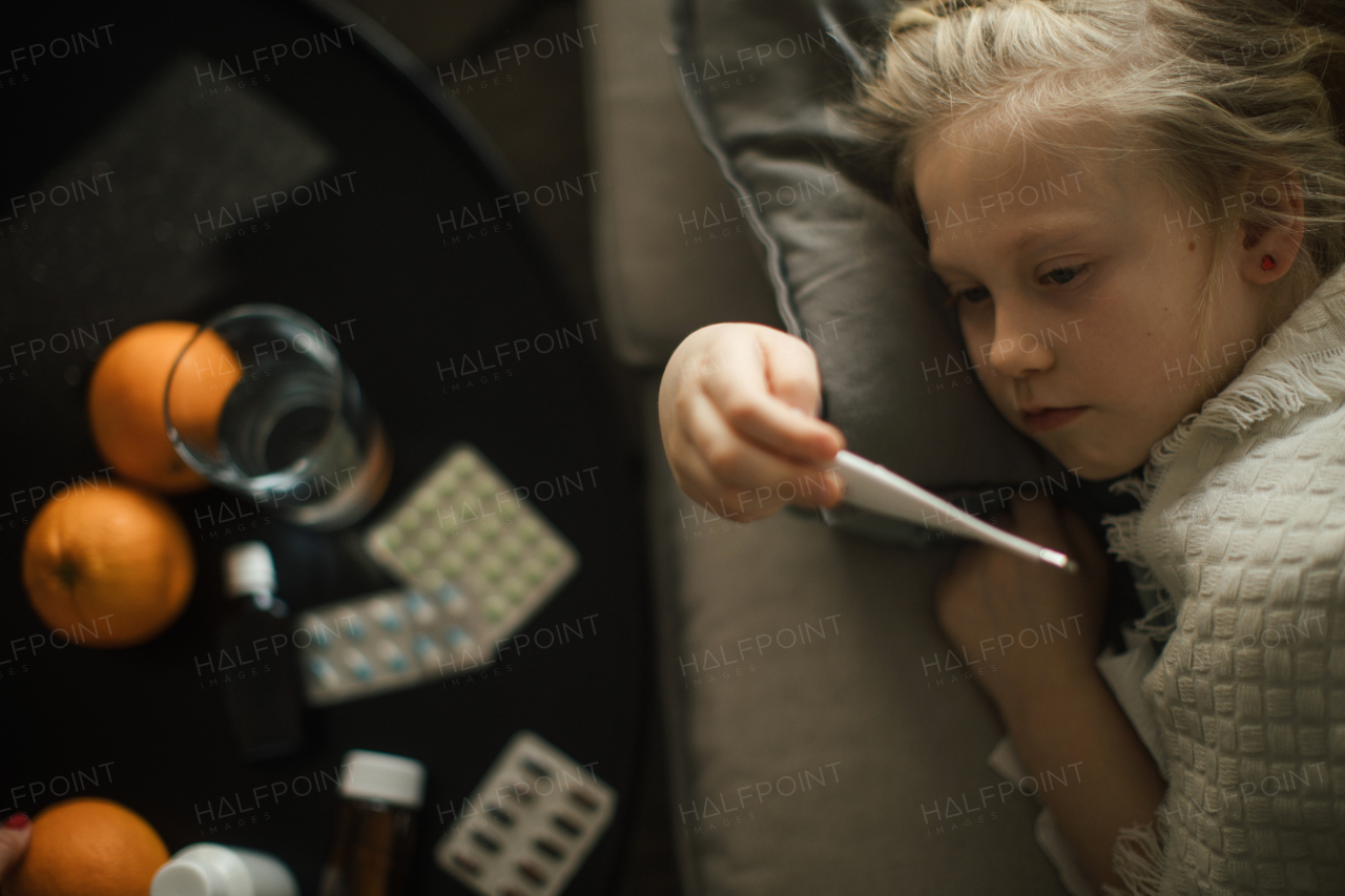 Little sick girl measuring the body temperature.