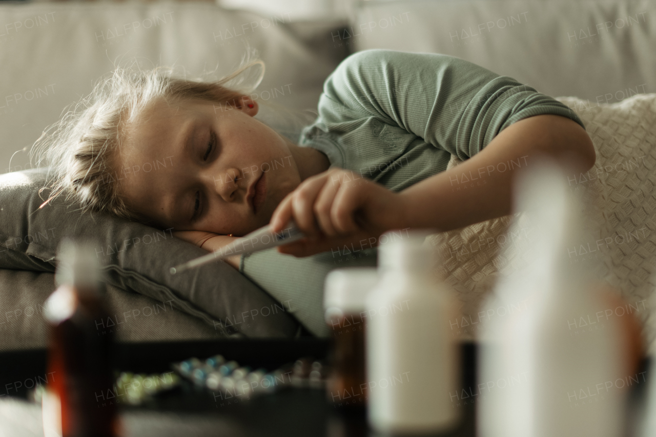 Little sick girl measuring the body temperature.