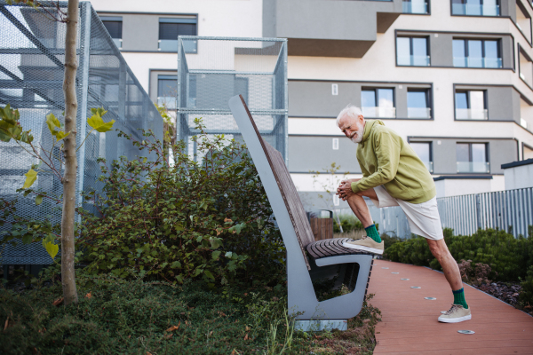 Senior man exercising and stretching outdoors in the city. An older, vital man leads an active lifestyle, going for a run every day.