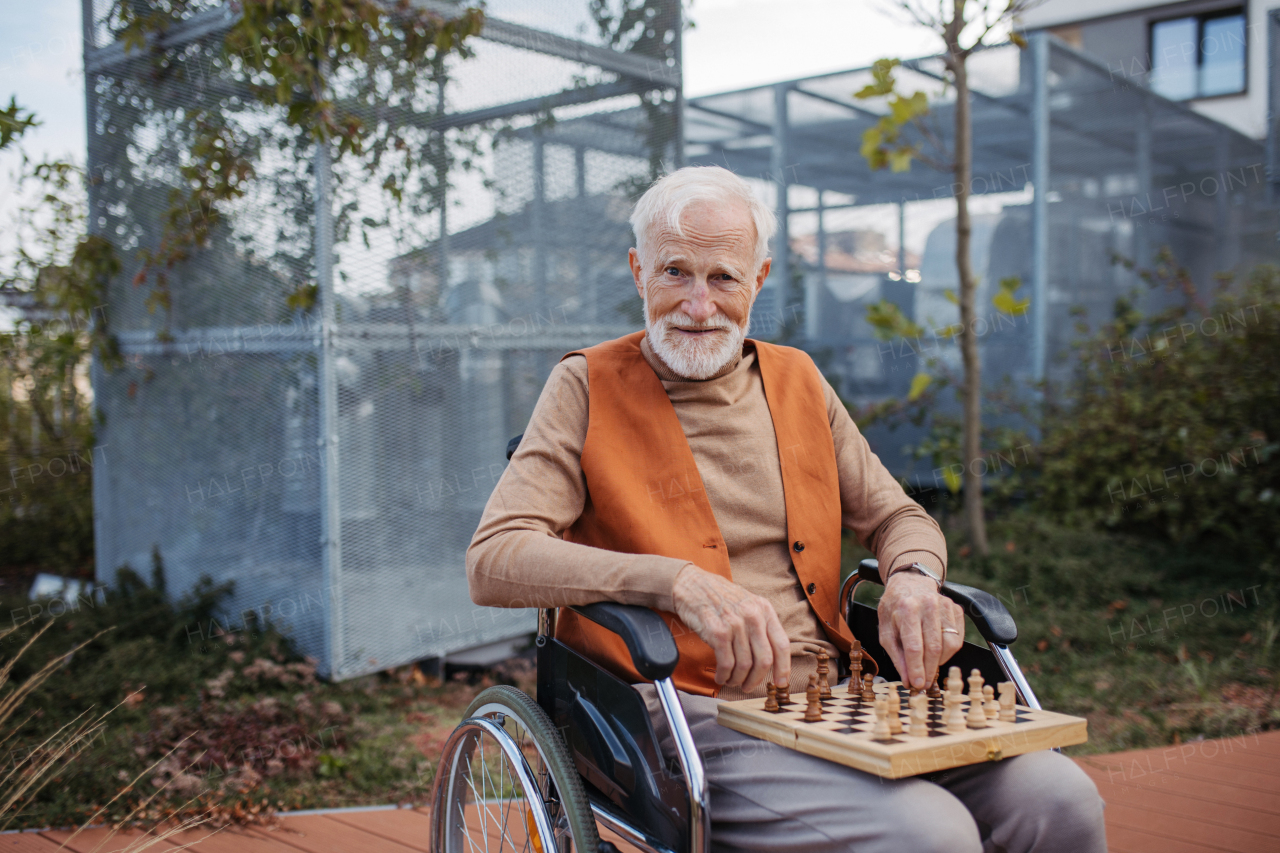 Senior man playing chess outdoors alone. Nursing home client, enjoying a game of solitaire chess, chess puzzle.