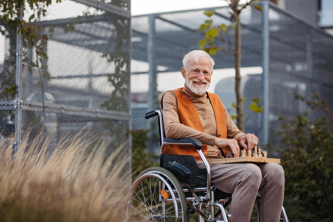 Senior man playing chess outdoors alone. Nursing home client, enjoying a game of solitaire chess, chess puzzle.