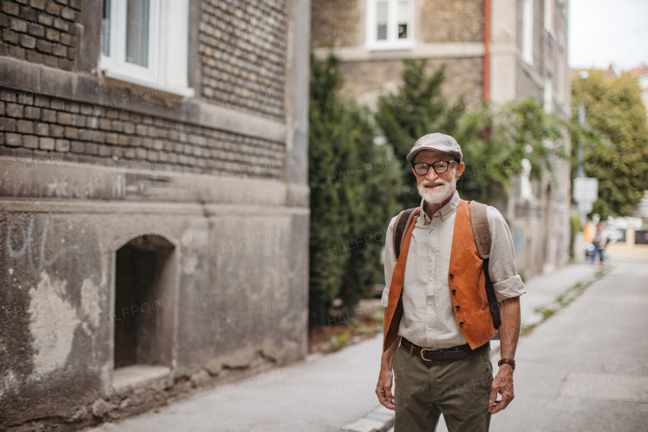 Portrait of handsome senior man in city. Elderly cool man strolling through city in fashionable clothes.