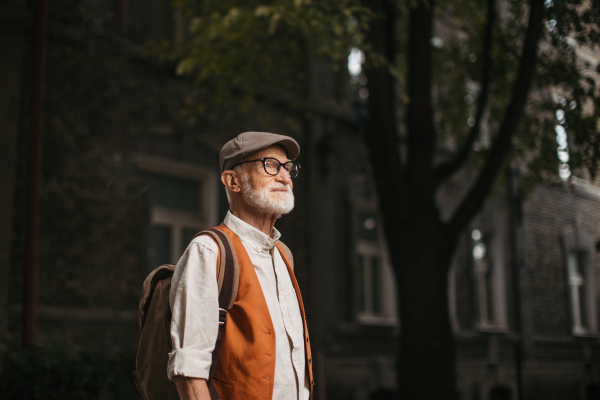 Senior tourist exploring a new city, exploring interesting places. Portrait of elderly man with beret. Traveling and trips in retirement.