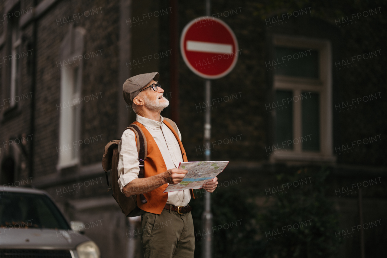 Senior tourist exploring a new city, exploring interesting places. Elderly man holding a paper map and looking for the route. Traveling and trips in retirement.