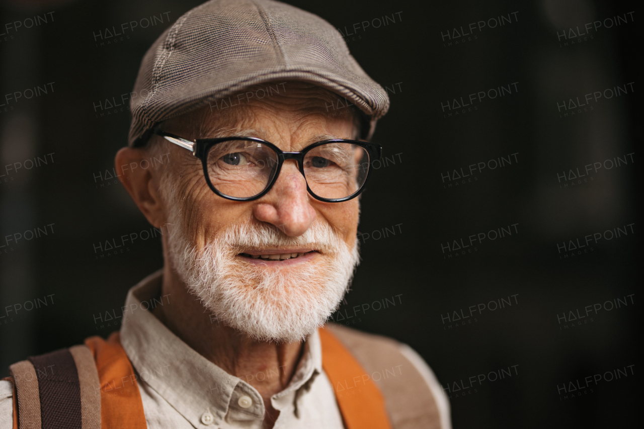 Studio portrait of a senior man with glasses and a beret on his head. Handsome smiling elderly man.