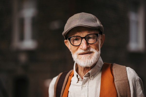 Studio portrait of a senior man with glasses and a beret on his head. Handsome smiling elderly man.