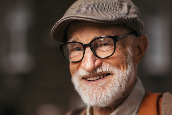 Studio portrait of a senior man with glasses and a beret on his head. Handsome smiling elderly man.