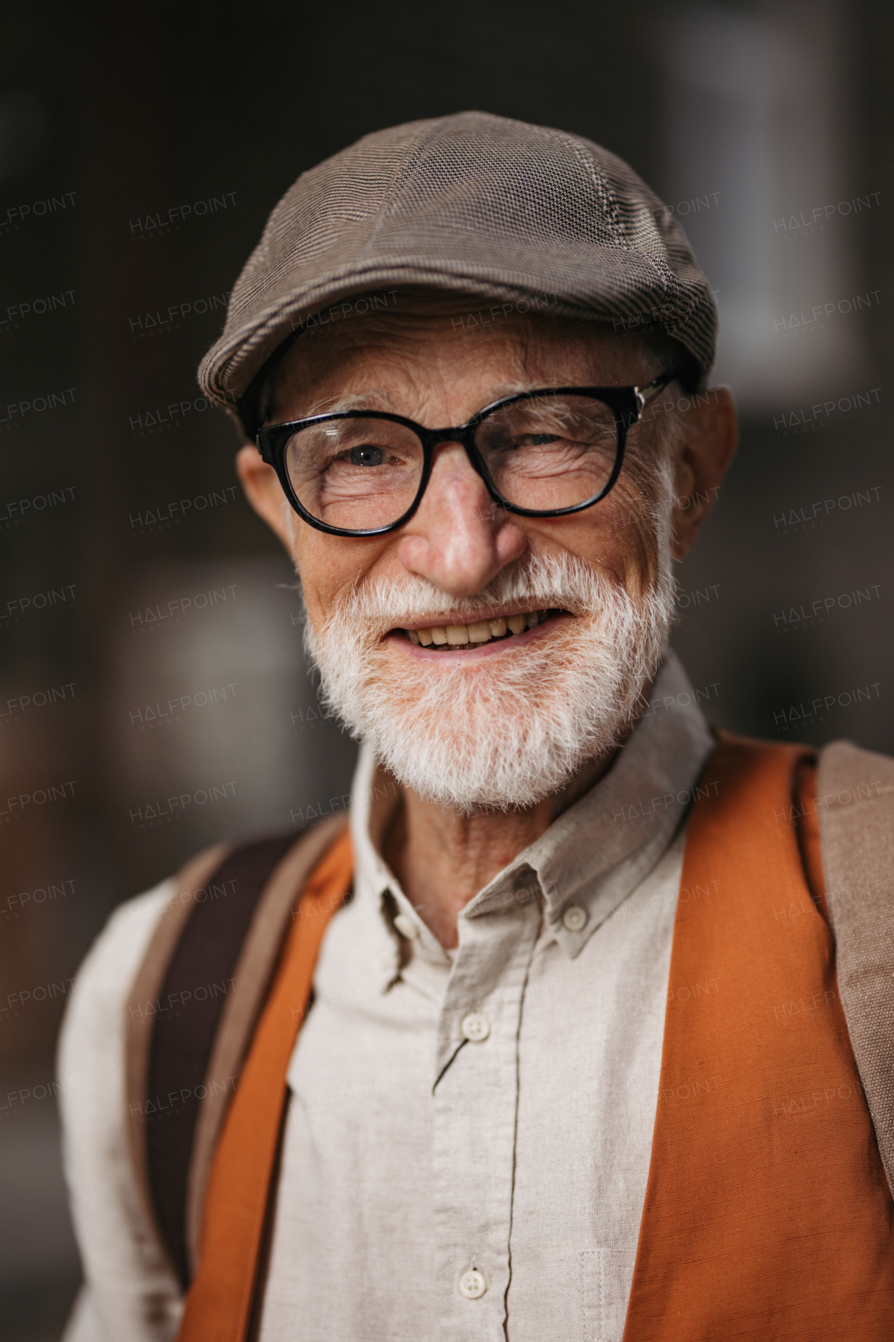 Studio portrait of a senior man with glasses and a beret on his head. Handsome smiling elderly man.