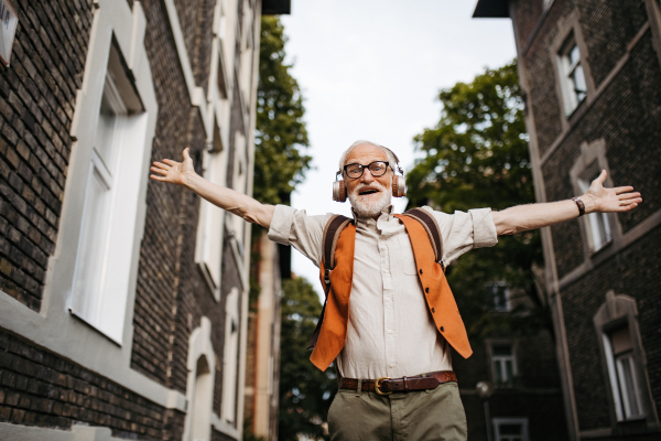 Close up shot of a senior man on the street. Elderly cool man listening to music outdoors, having fun. Concept of old man young at heart.