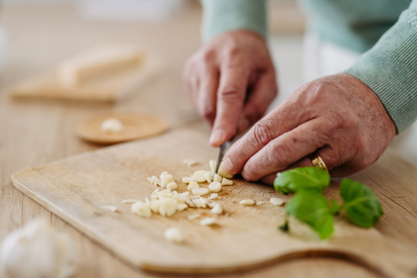 Close up of senior man cutting a garlic.