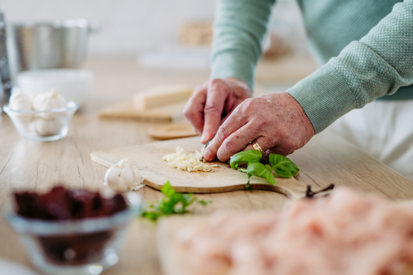 Close up of senior man cutting a garlic.