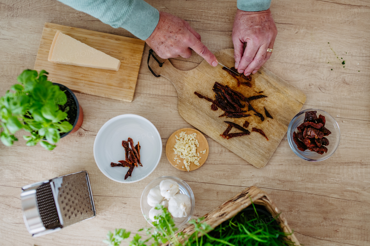 Close up of senior man cutting a dried tomatoes.