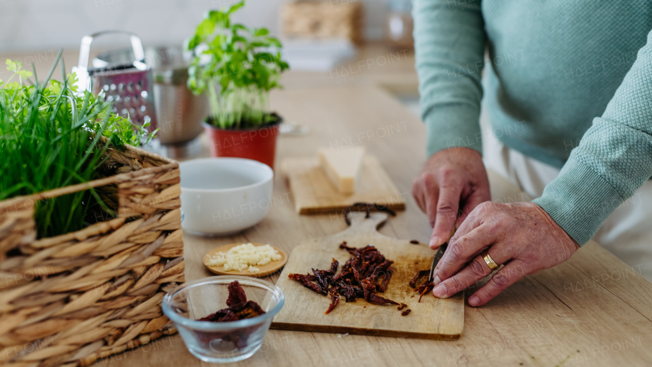 Close up of senior man cutting a dried tomatoes.