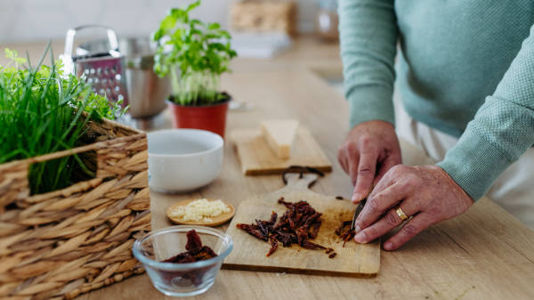 Close up of senior man cutting a dried tomatoes.