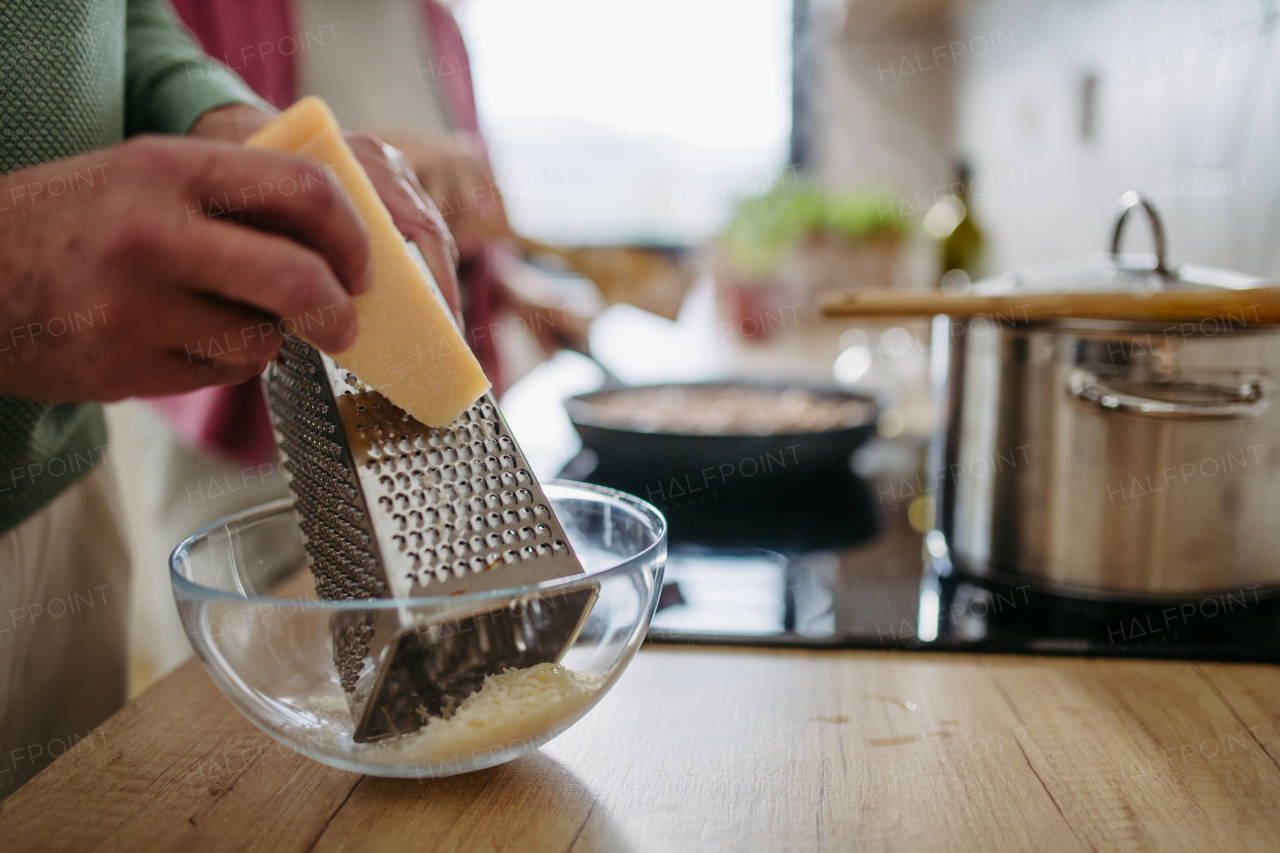 Close up of a senior man grating cheese during cooking.