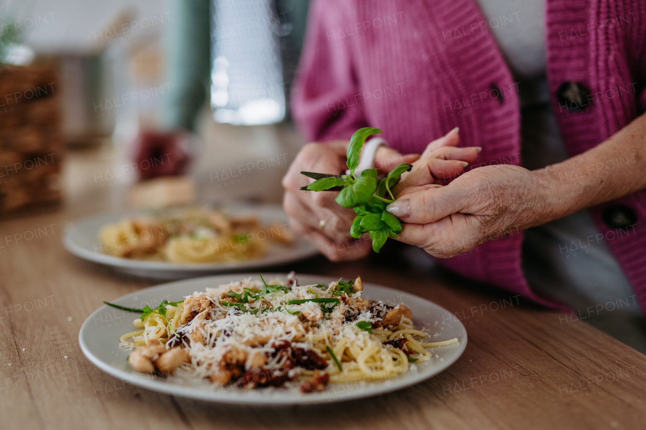 Cooking pasta with basil in the kitchen. Seasoning dishes with herbs