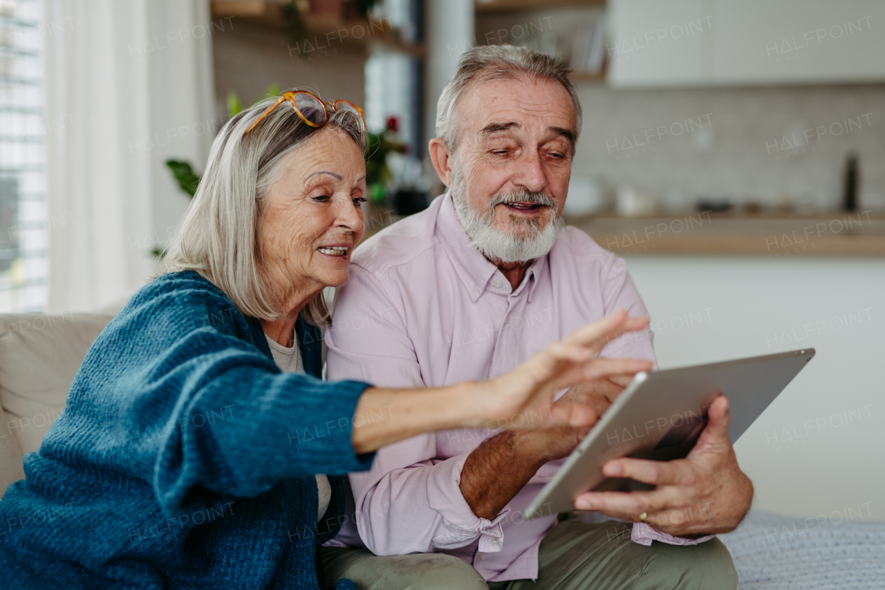 Senior couple scrolling tablet in the livingroom.