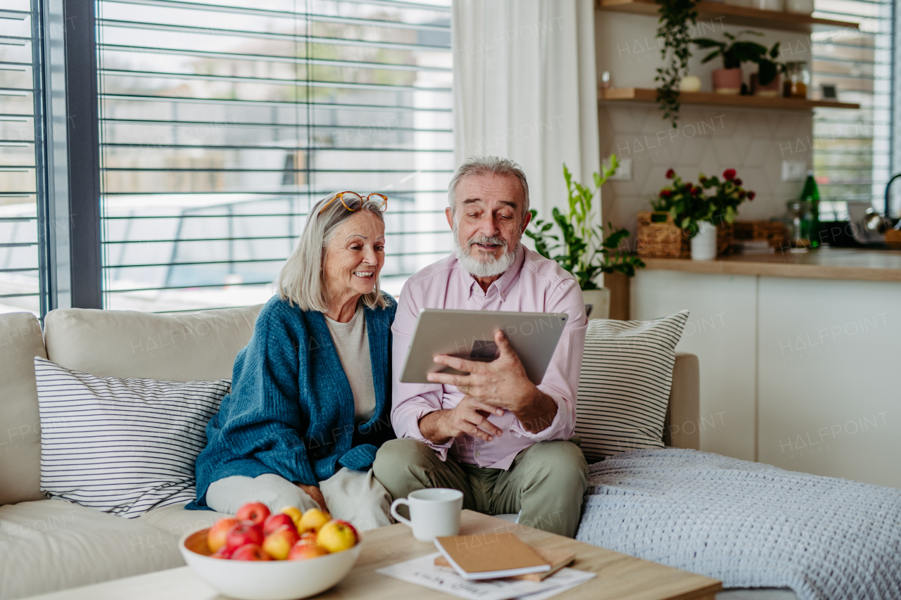 Senior couple scrolling tablet in the livingroom.