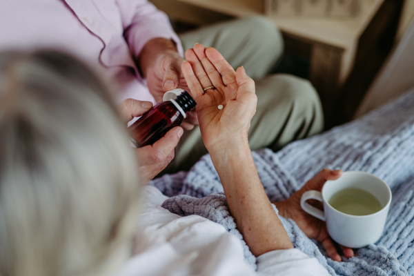 Close up of senior man giving pills to his ill wife.