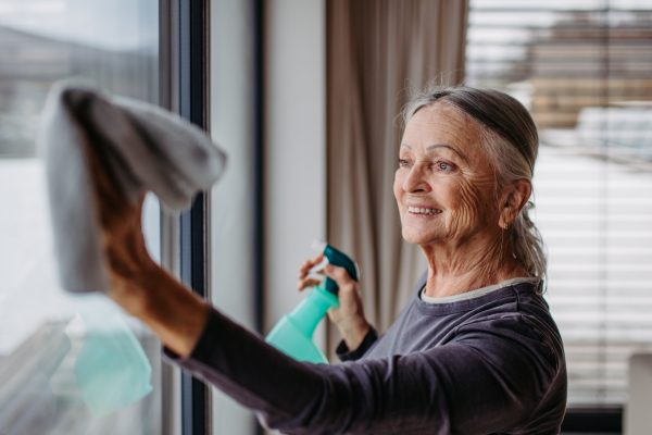 Senior woman cleaning windows, tidy up the house.